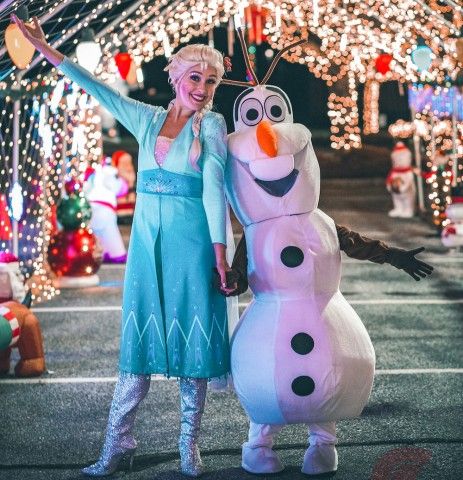 photograph of costume characters Elsa and Olaf from Disney's Frozen stand in front of Christmas lights