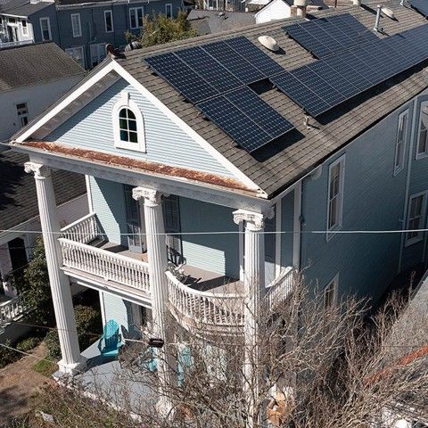 An aerial view of a historic house with solar panels on the roof