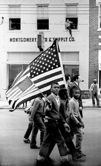 Young civil rights activists with American flags march towards the State Capital Building.
